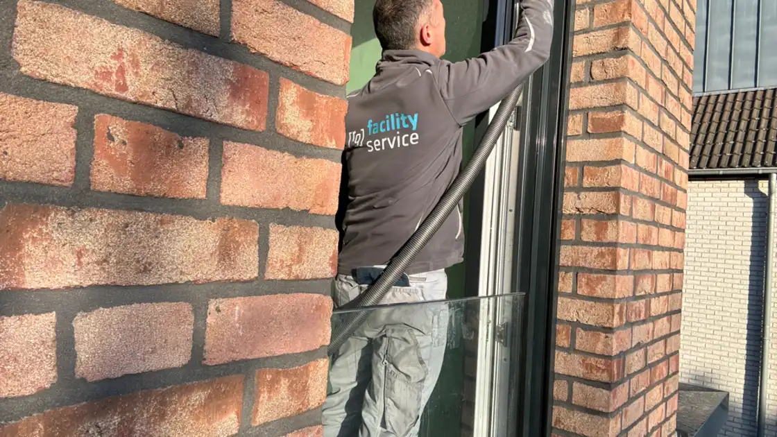 Ein Mann saugt einen Fensterrahmen ab