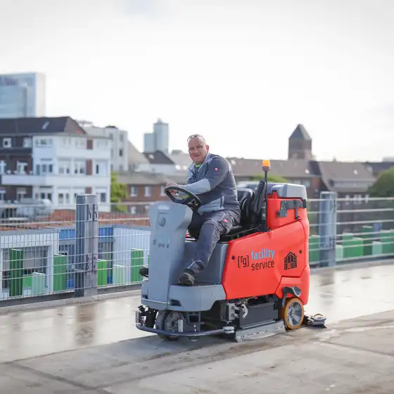 Ein Mitarbeiter fährt mit einer Kehrmaschine über ein Parkhausdeck