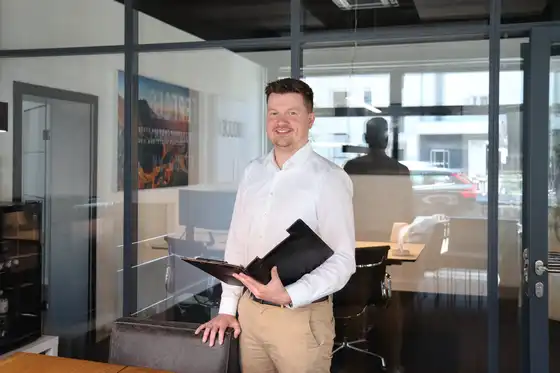 Ein Mann steht am Schreibtisch und hält eine geöffnete Schreibmappe